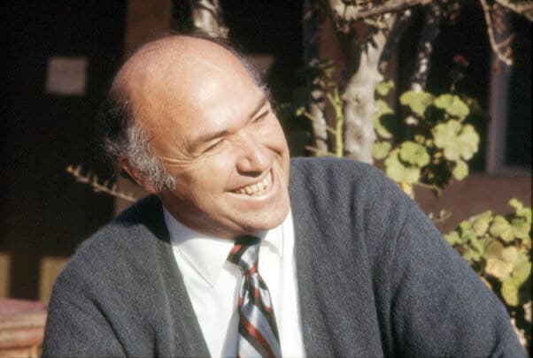 Pastor Chuck Smith in a cardigan and striped tie, laughing in the sunshine.